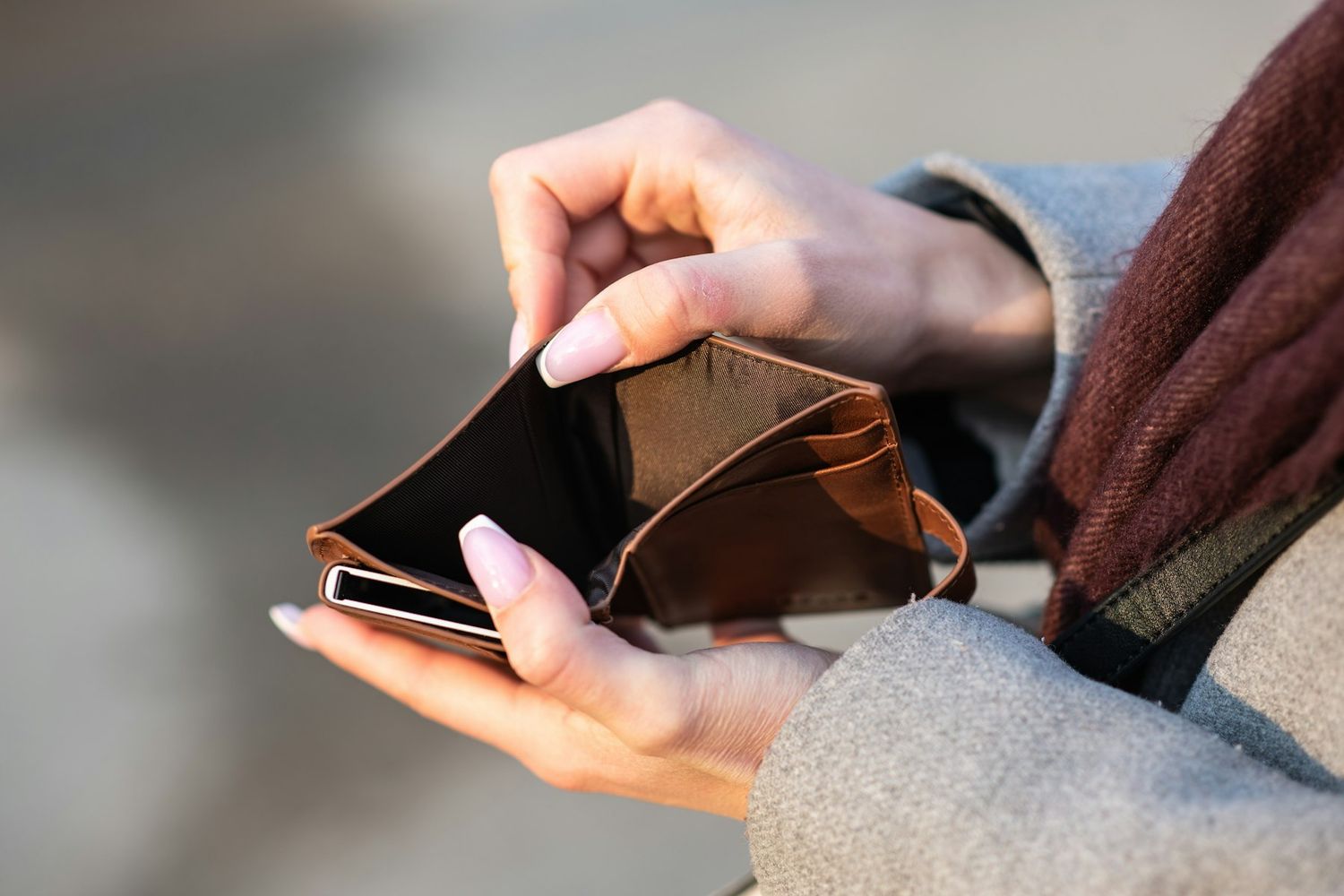 Two hands prising open a leather wallet. It&rsquo;s empty.