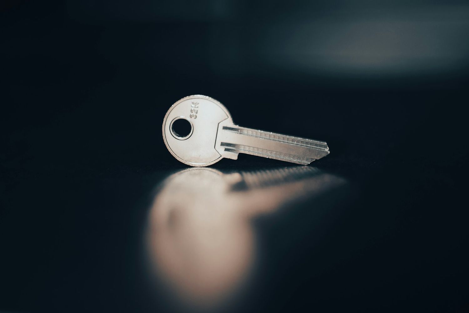 A single key lying on a dark surface.